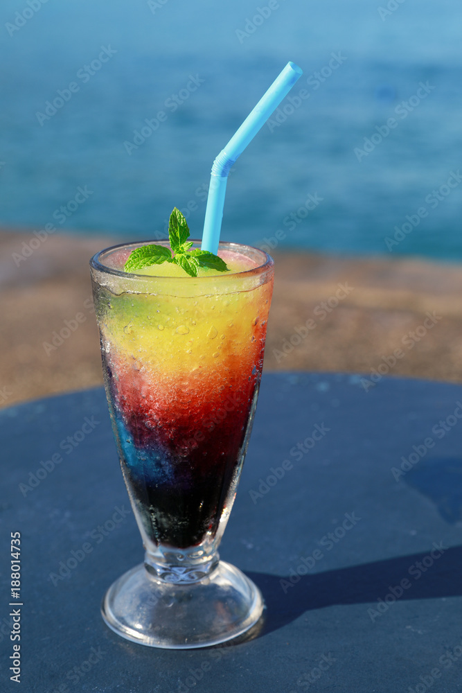 A glass of frozen fruit slush granita drink on the table by the sea.