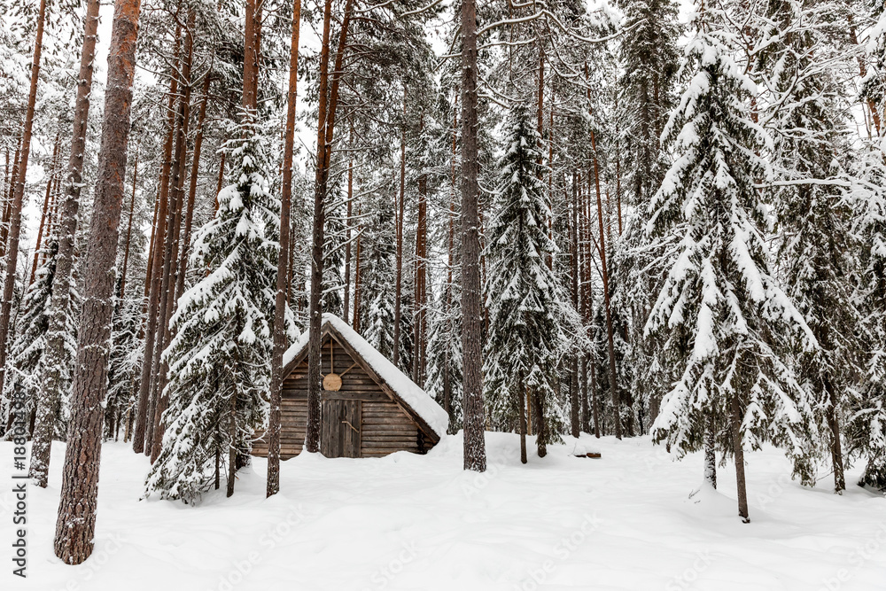 a wooden house in the snow-covered forest near The Raudanjoki river, Rovaniemi, Finland. a wooden house in the snow-covered forest near The Raudanjoki river, Rovaniemi, Finland.