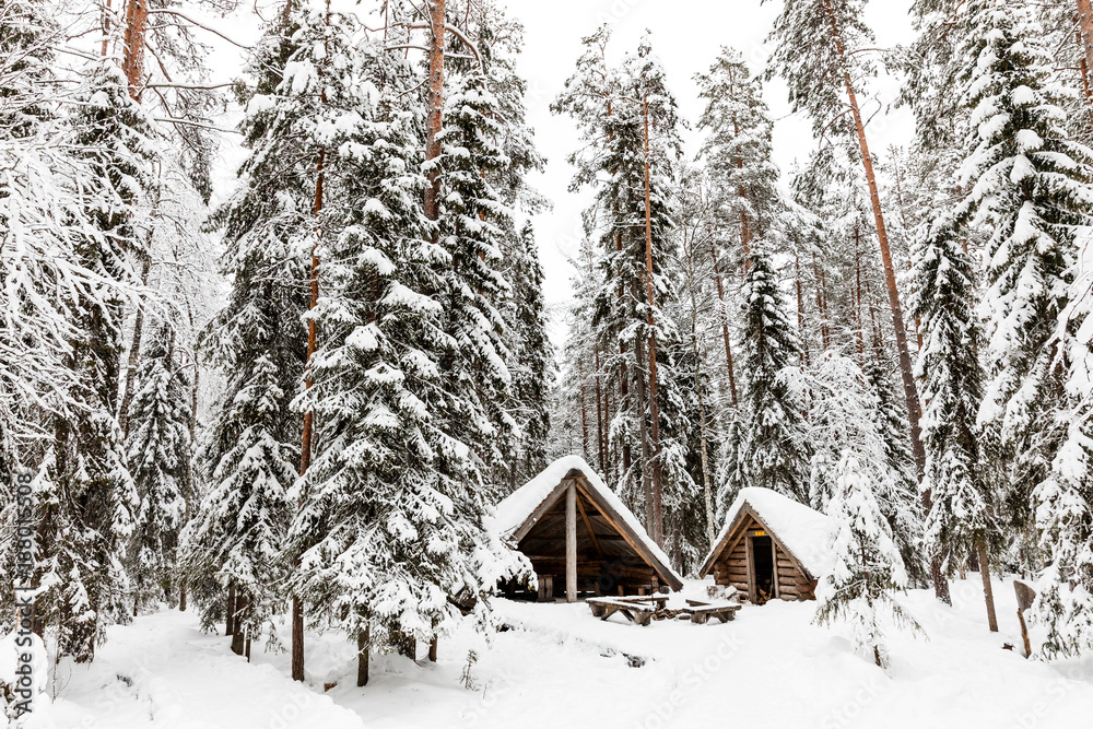 a wooden house in the snow-covered forest near The Raudanjoki river, Rovaniemi, Finland.