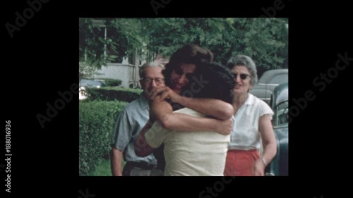 1956 Family hugs and kisses goodbye in front of vintage antique cars