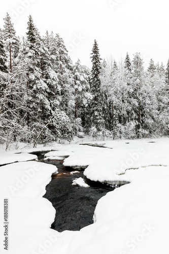 snow-covered forest and The Raudanjoki river, Rovaniemi, Finland.