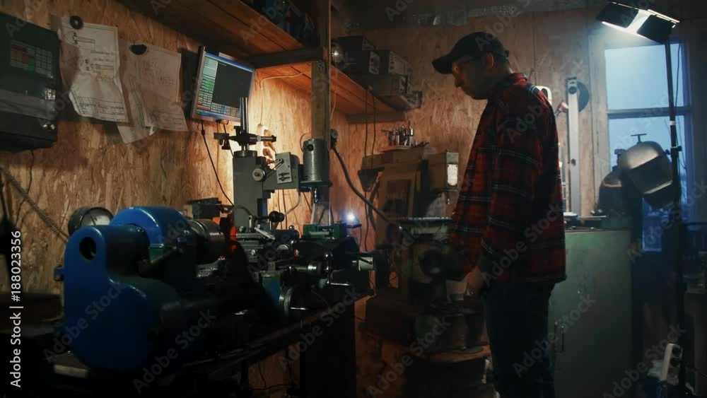 male master engineer manages cnc drilling machine in a dark workshop garage male master engineer manages cnc drilling machine in a dark workshop garage