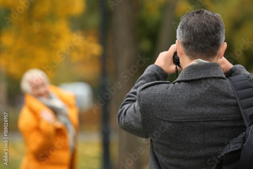 Man taking photo of mature woman in park