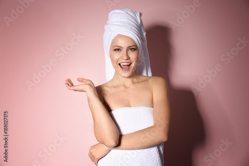 Attractive young woman in white towel on color background