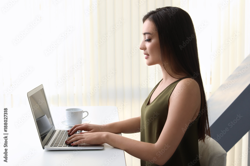 Young woman working with modern laptop at table