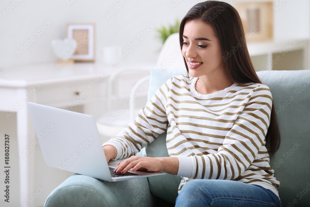 Young woman with modern laptop sitting on sofa at home Young woman with modern laptop sitting on sofa at home