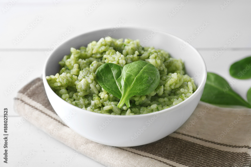 Dish with delicious spinach risotto on wooden table Dish with delicious spinach risotto on wooden table