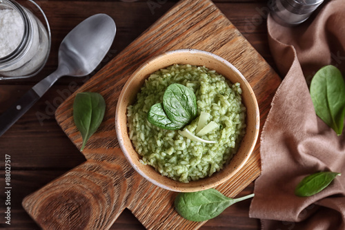 Dish with delicious spinach risotto on wooden board