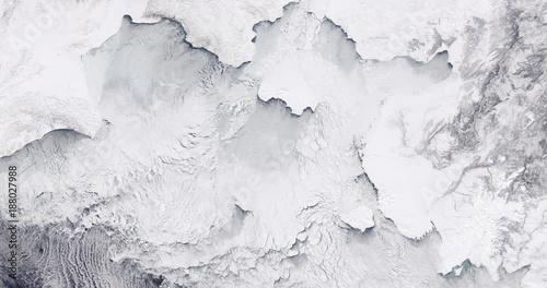 Very high-altitude overflight aerial of ice sheets and sea ice, northern Bering Sea coast. Clip loops and is reversible. Elements of this image furnished by USGS/NASA Landsat photo