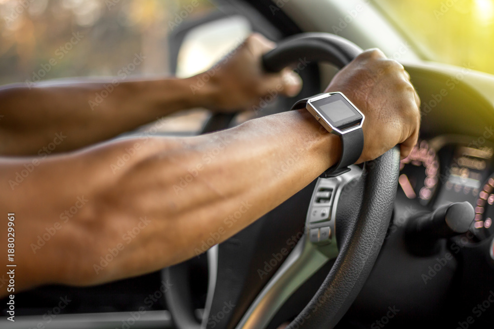 Man who wearing smart watch is driving vehicle while working or going to somewhere with the flare from the outside.
