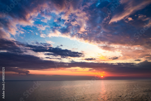 Colorful sunset over calm sea in summer with sun beam