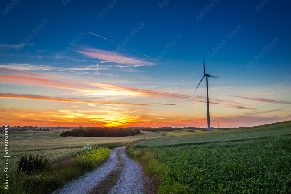 Stunning dusk over green field wind turbines in summer
