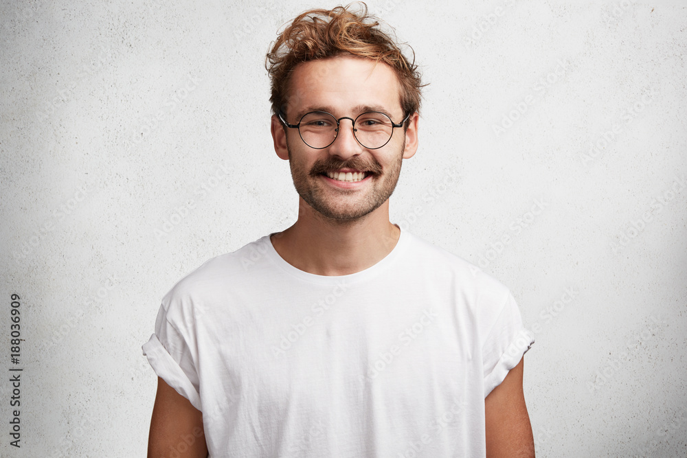 © wayhome.studio - Horizontal shot of satisfied content bearded male wonk has happy smile on face, glad to achieve great results and get award for his work, dressed casually, isolated over white concrete wall. © wayhome.studio - Horizontal shot of satisfied content bearded male wonk has happy smile on face, glad to achieve great results and get award for his work, dressed casually, isolated over white concrete wall.
