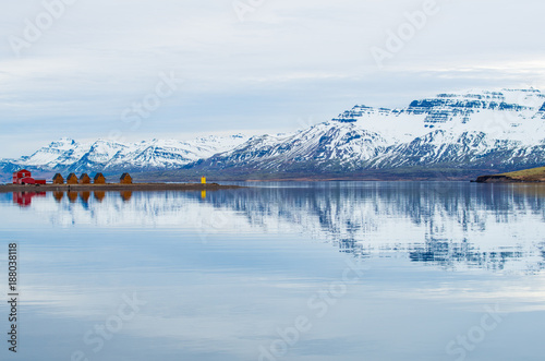 The reflection of the small cottage and snowcap mountains in Mjoeyri of Eskifjörður town in east Iceland.