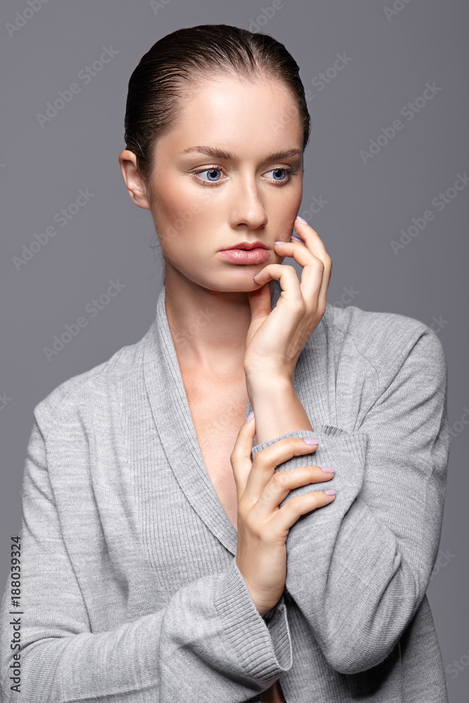 Beauty portrait of young woman in gray dress. Brunette girl with bright blue eyes and day female makeup Beauty portrait of young woman in gray dress. Brunette girl with bright blue eyes and day female makeup