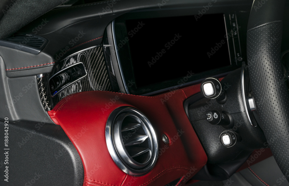 AC Ventilation Deck in Luxury modern Car Interior. Modern car interior details with red and black leather with red stitching. Carbon panel. Perforated leather steering wheel