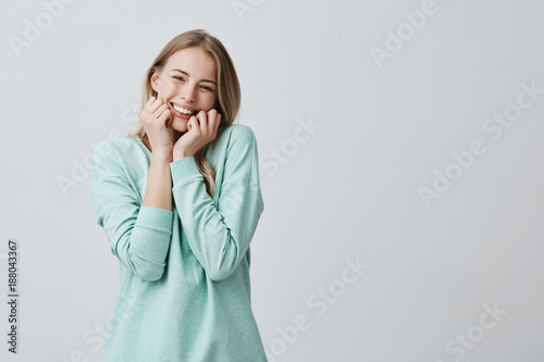 Headshot of cute blonde woman with luminous dark eyes, glowing face and gentle smile rejoicing her success. Cheerful delighted female having birthday party. Facial expression and positive emotions