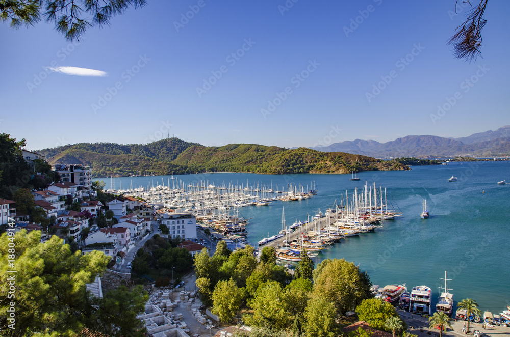 Fototapeta premium Turkey, Fethiye, view of the harbor with numerous yachts, and beautiful mountains in the background in the rays of the sun
