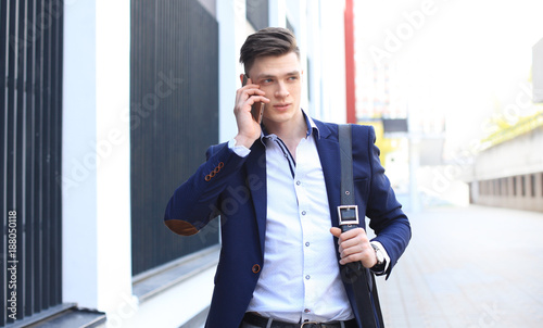 Young urban businessman professional on smartphone walking in street using mobile phone.