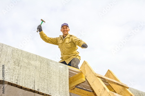 The man is working on the roof, waving a hammer photo