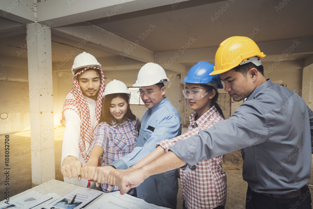 Asian engineers were consulted together and trust in team giving fist bump to plan in construction site Asian engineers were consulted together and trust in team giving fist bump to plan in construction site