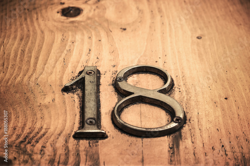 eigthteen number on wooden table. Solid sign made of metal photo