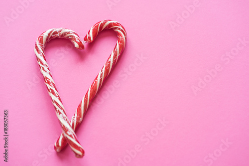 Heart of two candy canes on the pink background. Colorful background. Copy space for text.