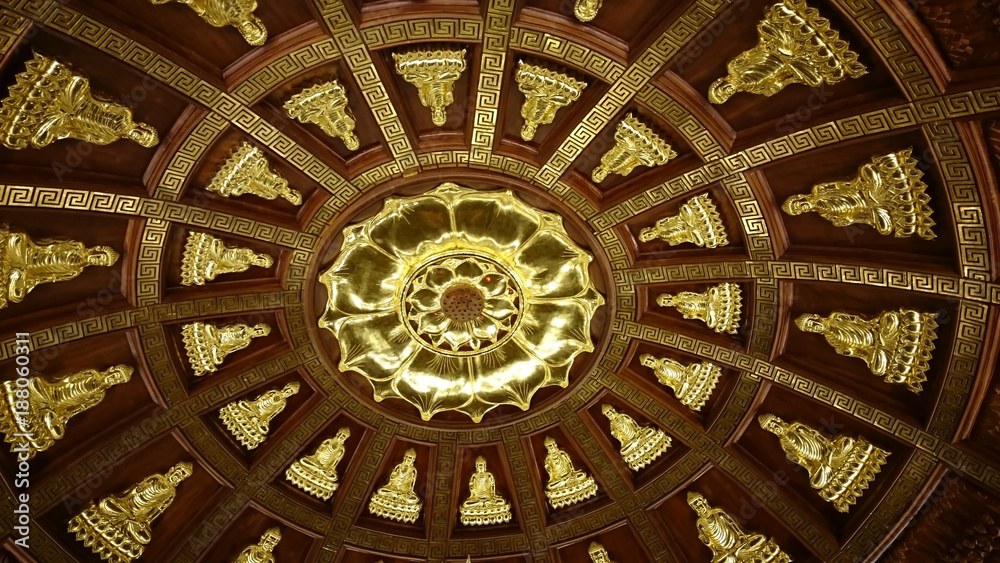 Shiny metal relief silhouettes of Buddha- probably gold - in buddhist temple of Ninh Binh, Vietnam, South-East Asia. Highly decorative ceiling covered with sitting figures radial pattern.