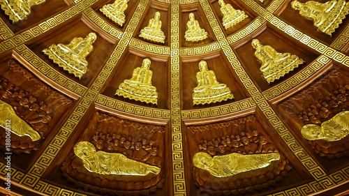 Shiny metal relief silhouettes of Buddha- probably gold - in buddhist temple of Ninh Binh, Vietnam, South-East Asia. Highly decorative ceiling covered with sitting and laying figures radial pattern. 