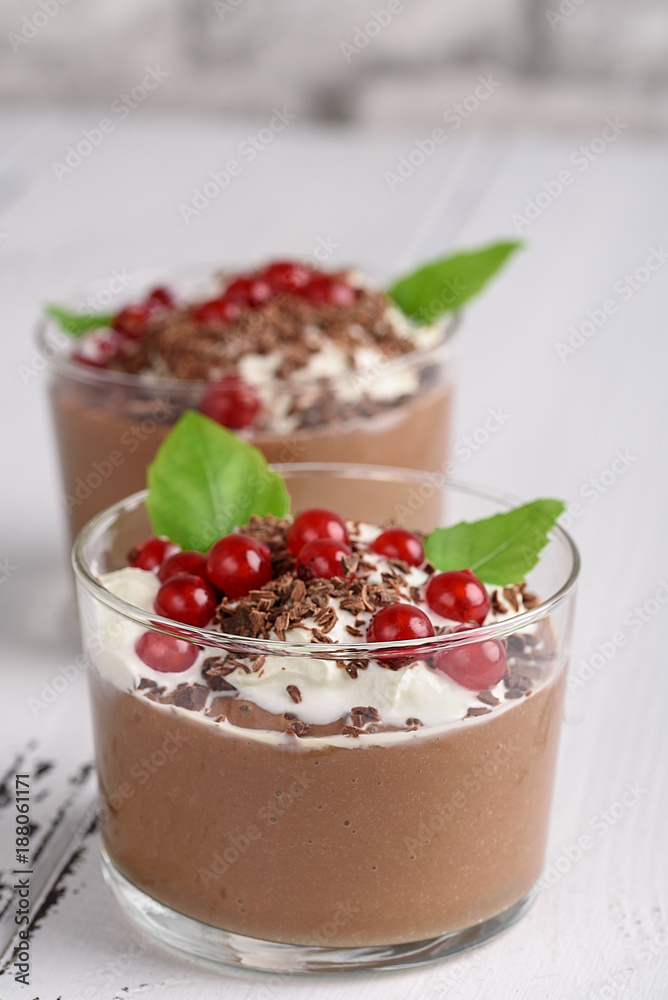 Chocolate mousse with currant and mint in a glasses on a whiite wooden background. Chocolate mousse with currant and mint in a glasses on a whiite wooden background.