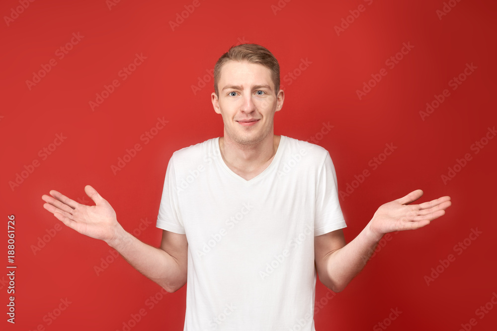 young attractive man in casual clothes helplessly throws up his hands with a surprised confused look on his face. Studio portrait on isolated background.