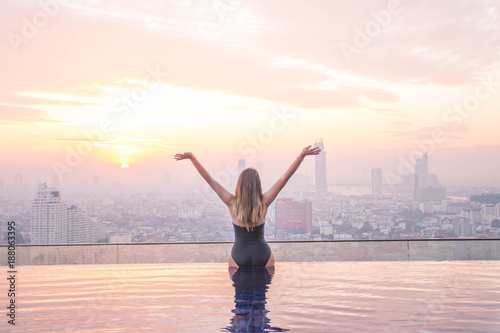 Sexy girl with her hands up meet the sunrise at infinity pool . Thailang, Bangkok.