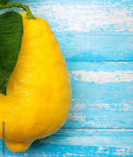 Lemon with leaf. On cyan wooden table, background.Giant lemon.Closeup.Copy space photo