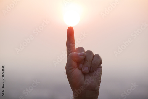 Fingers pointing at the sun with pink morning background