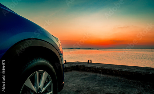 Blue compact SUV car with sport and modern design parked on concrete road by the sea at sunset. Environmentally friendly technology. Business success concept. © Artinun