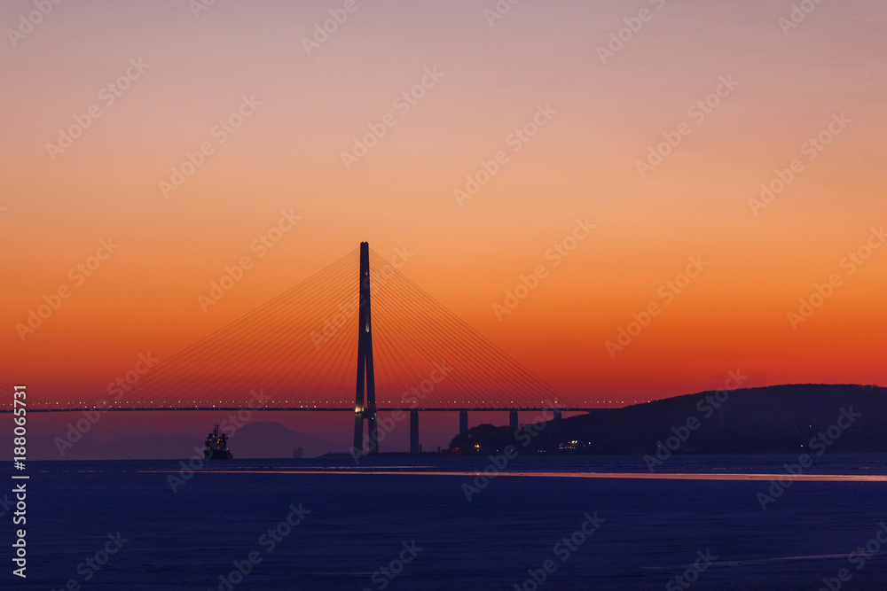 Obraz premium Amazing zooming out aerial view of the Russky Bridge, the world's longest cable-stayed bridge, and the Russky (Russian) Island in Peter the Great Gulf in the Sea of Japan. Sunrise. Vladivostok, Russia