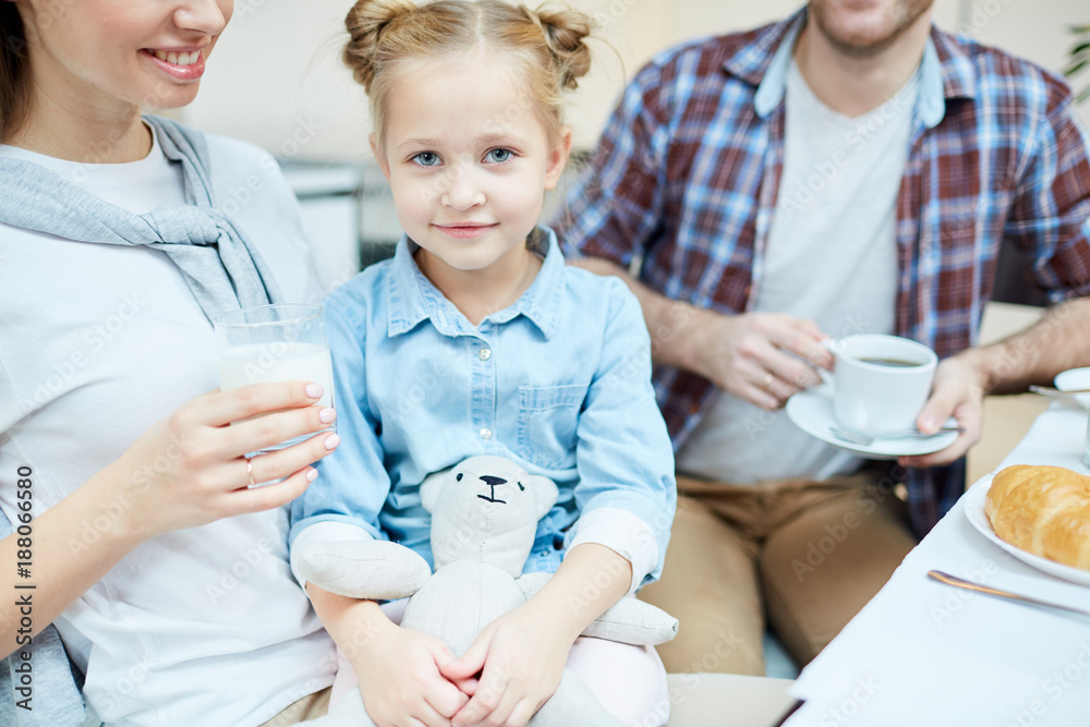Adorable girl with teddie sitting on her mother knees with father near by Adorable girl with teddie sitting on her mother knees with father near by