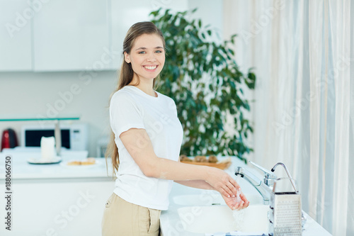 Healthy young woman washing her hands with pure water from kitchen tap