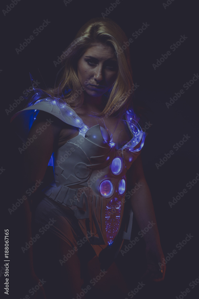 blond woman of the future wearing white latex suit and blue led lights on dark background