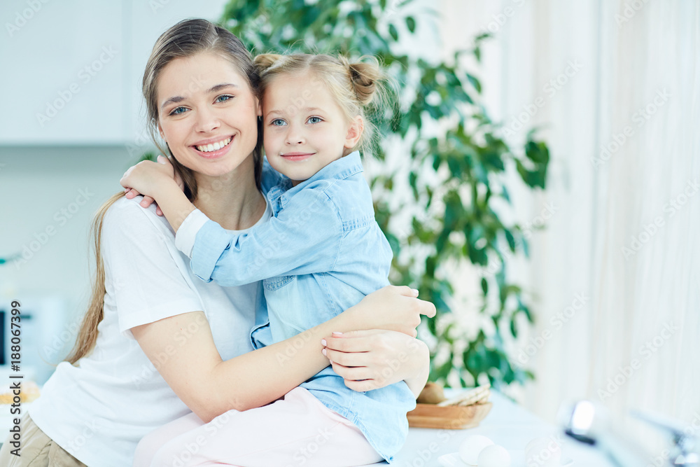 Cheerful and affectionate mother and daughter in embrace spending time at home Cheerful and affectionate mother and daughter in embrace spending time at home