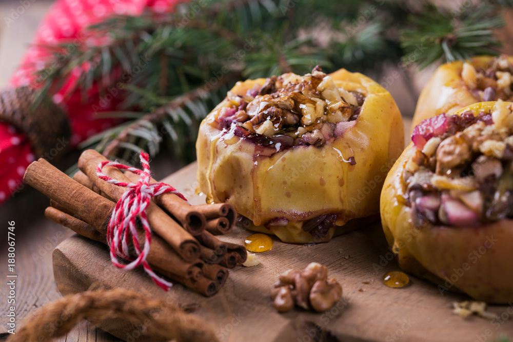 Baked apples stuffed with berries, walnuts and honey on a wooden cutting board.