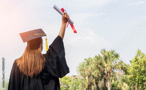 happy graduate showing certificated in hand with sky background photo
