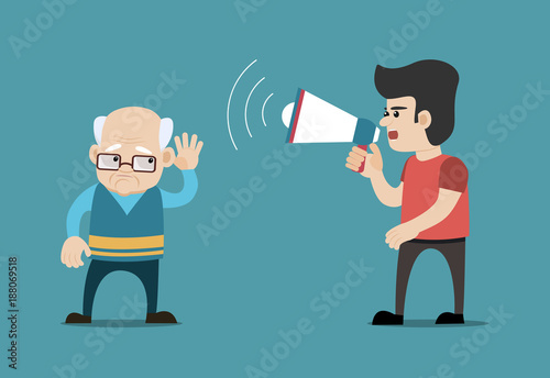 Young man shouting with megaphone at hearing impaired senior man photo
