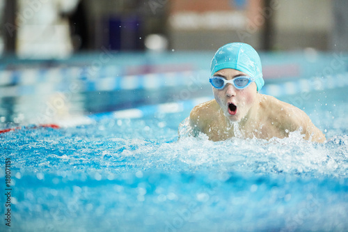 Young boy in swim-cap and goggles practicing swimming or preparing for competition
