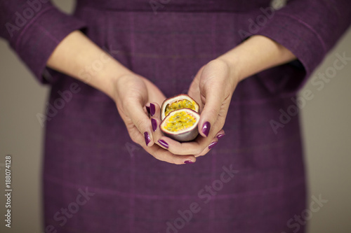 woman in violett 50's dress hands holding some passion fruits, sensual studio shot can be used as background photo