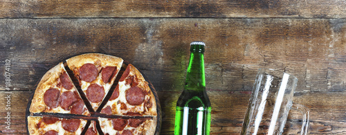 Beer and pepperoni pizza on a wooden table in a pub or pizzeria