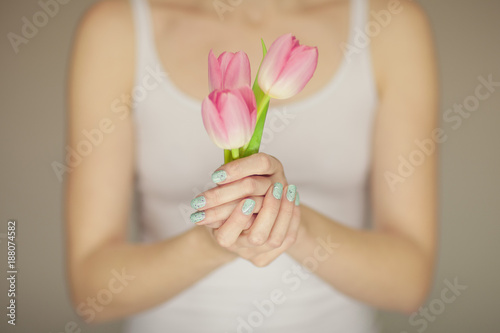 woman hands with perfect nail art holding pink spring flowers tulips, sensual studio shot can be used as background