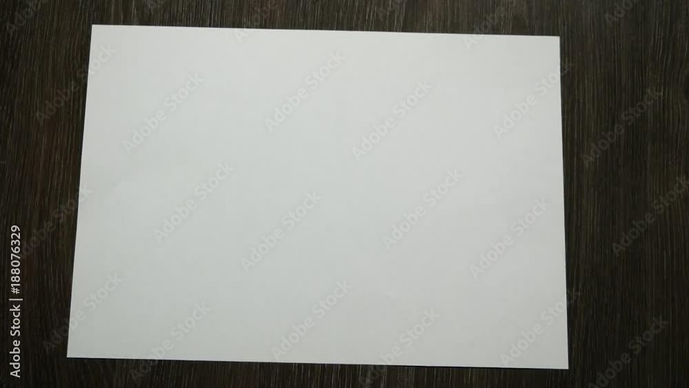 White paper for notes falls on a dark wooden table. Slow motion