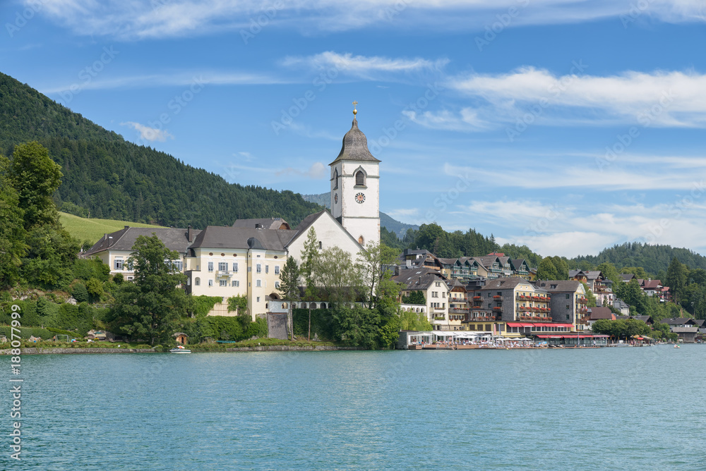 View from lake Wolfgangsee to the Pilgrimage church of St. Wolfgang and the small town St. Wolfgang im Salzkammergut under blue sky with white clouds, Upper Austria, Austria, Europe