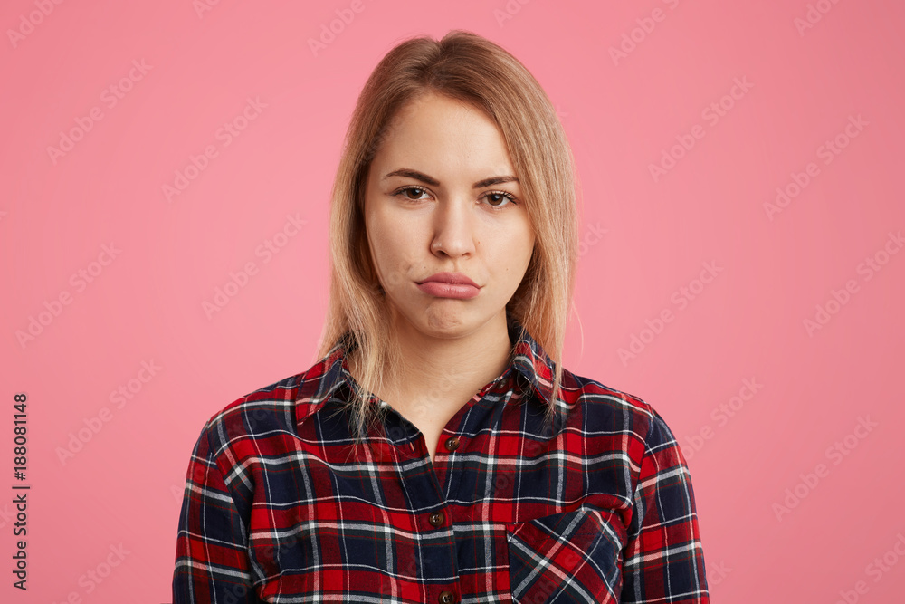 Attractive abused female model curves lips as being offended by close person, expresses her dissatisfaction, isolated over pink background. Depressed beautiful woman with dipleased expression Attractive abused female model curves lips as being offended by close person, expresses her dissatisfaction, isolated over pink background. Depressed beautiful woman with dipleased expression